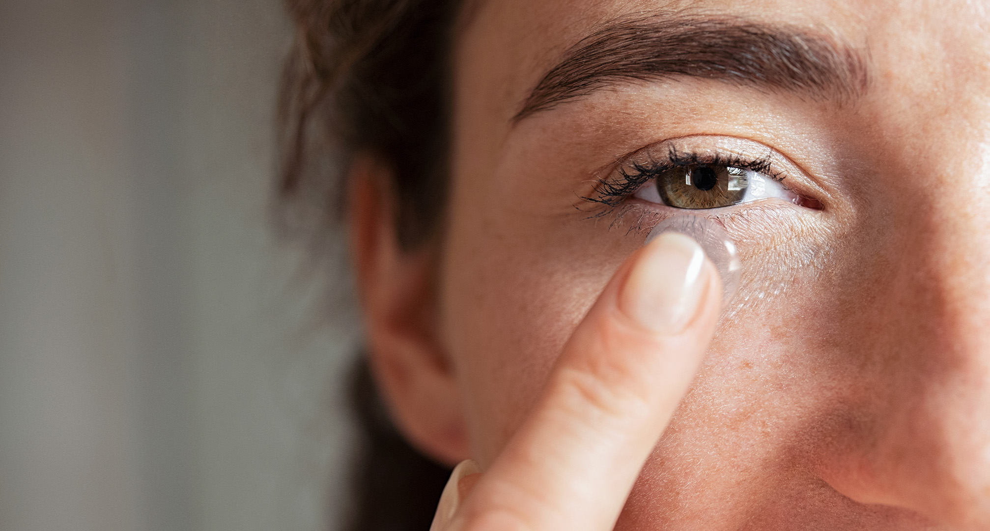 close up of person holding contact lens in front of eye 