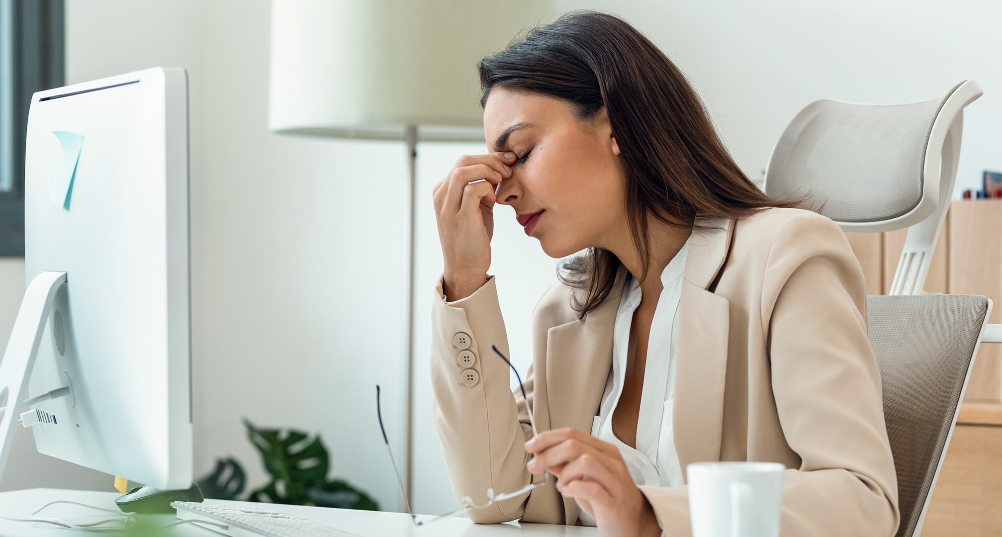 person squinting from eye strain at desk with glasses