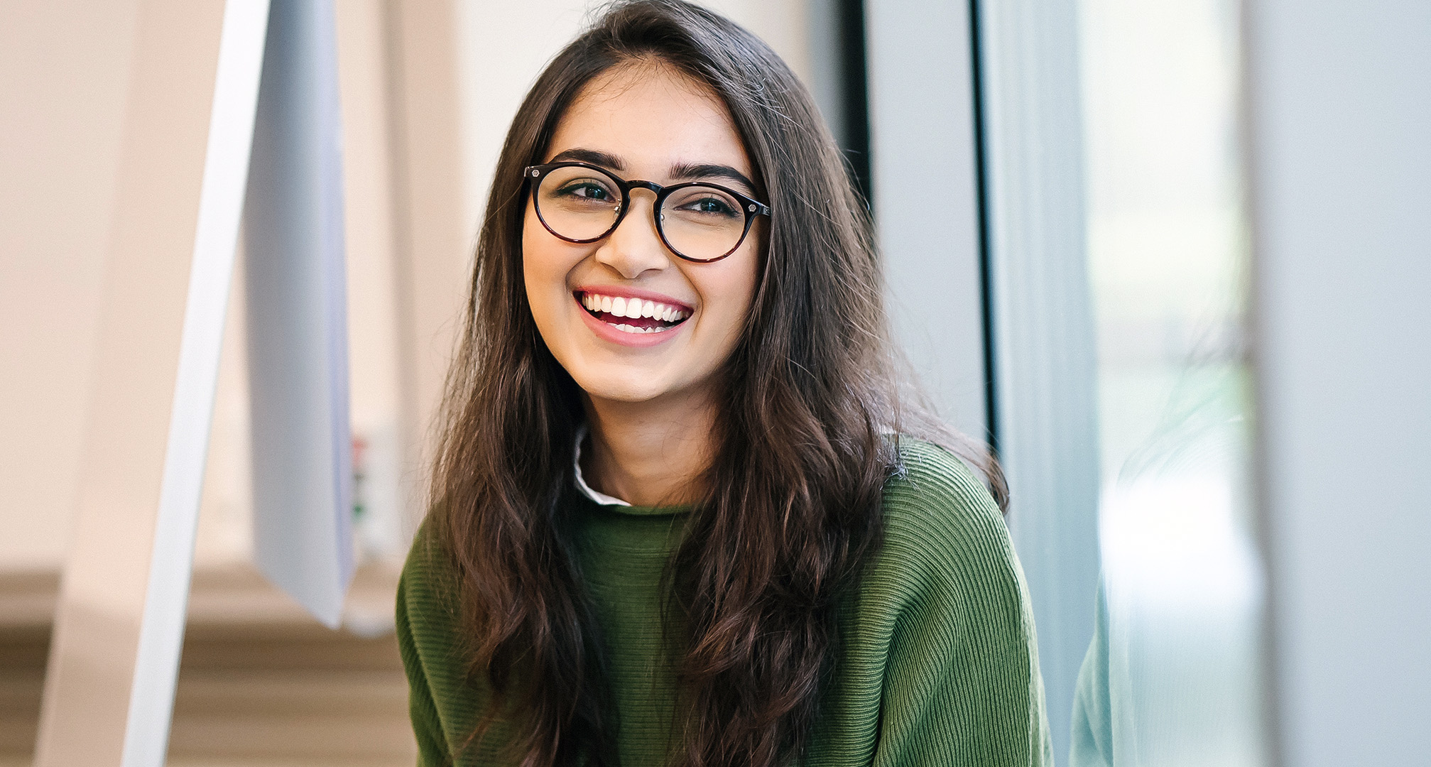 photo a smiling person with long hair wearing black glasses frames